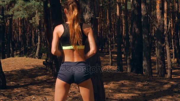 Горячая спортивная девушка в коротких шортах с эластичными сексуальными ягодицами, прыгающая в лесу — стоковое видео