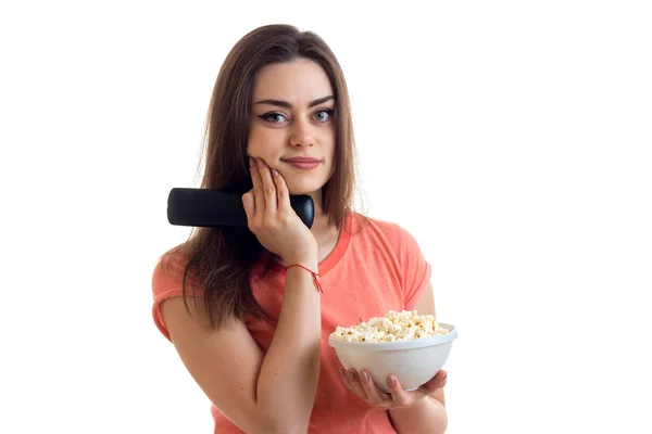 Retrato de uma jovem encantadora com controle remoto da TV e milho pop na mão — Fotografia de Stock
