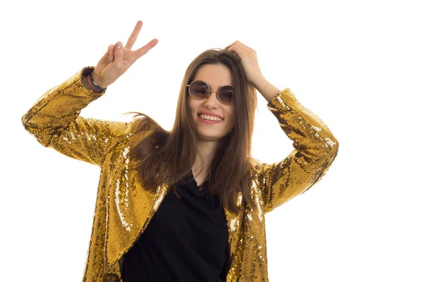 Chica glamour divertido en gafas y una chaqueta brillante muestra un gesto de la mano y sonriendo —  Fotos de Stock