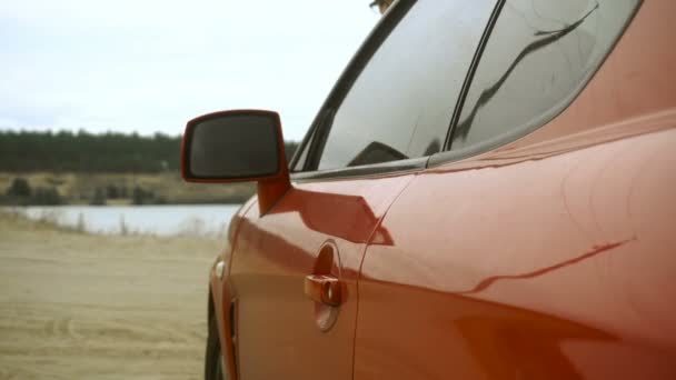 Σεξουαλική νεαρή κοπέλα με κόκκινα χείλη γλείφει ένα γλειφιτζούρι στο κόκκινο αυτοκίνητο — Αρχείο Βίντεο