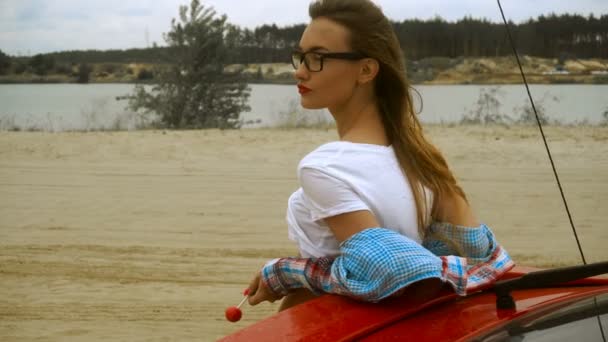 Atraktivní dáma s červenými rty a sluneční brýle olizuje lízátko — Stock video