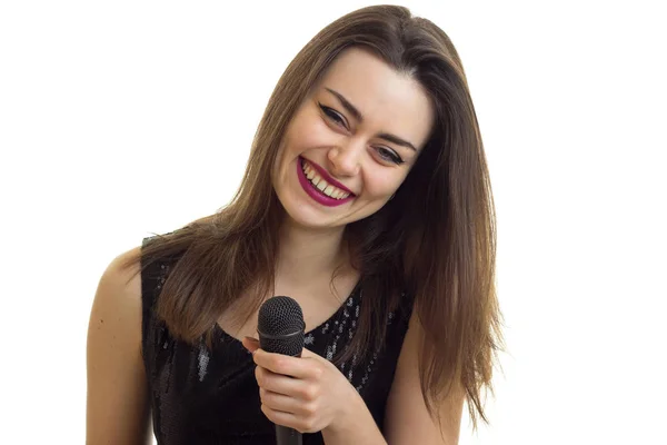 Alegre joven en vestido negro cantando un karaoke —  Fotos de Stock