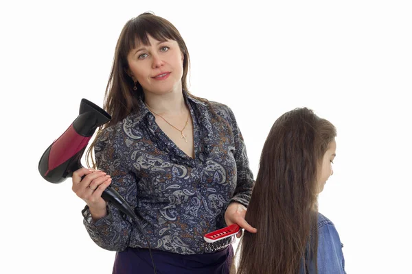 Madre con secador de pelo hace un peinado a su hija pequeña Fotos de stock libres de derechos