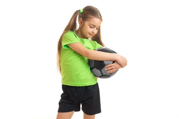 A little girl in a bright t-shirt stands in the Studio and hugs ball hands — Stock Photo, Image
