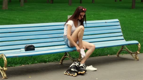 Uma jovem está sentada e coloca em seus rolos de pés — Vídeo de Stock