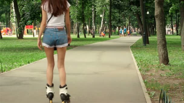 Young slim girl in shorts riding in the park — Stock Video