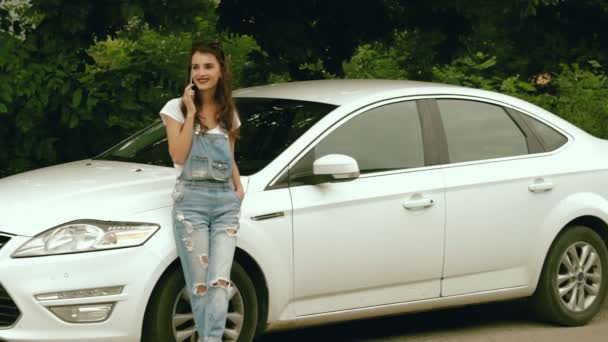 Glamouröse junge Frauen im Jeanskleid telefonieren in der Nähe ihres Autos — Stockvideo