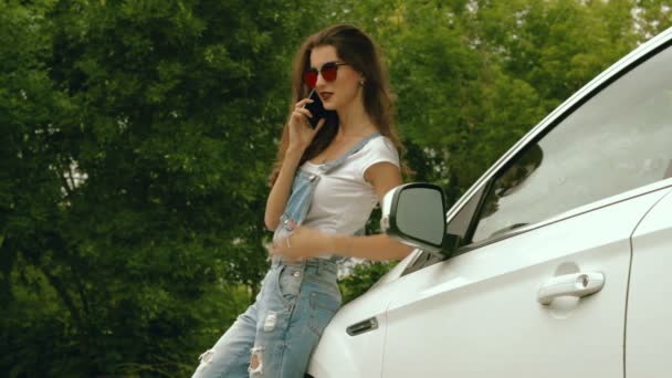 Sexig tjej i jeans klänning står nära maskinen och talar på telefon — Stockvideo