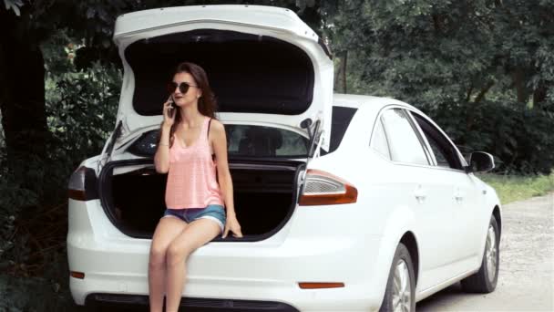 Hermosa chica sentada en un coche y hablando por teléfono — Vídeos de Stock