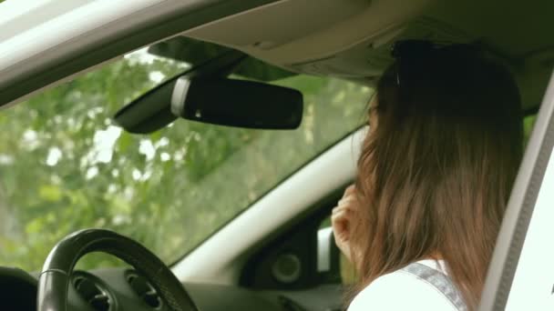 Trendy dame kijkt in de spiegel in de auto en verf lipgloss — Stockvideo