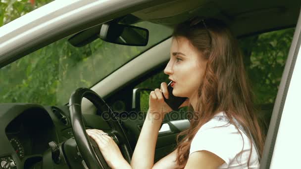 Młoda brunetka podczas jazdy w samochodzie, rozmawiając przez telefon — Wideo stockowe
