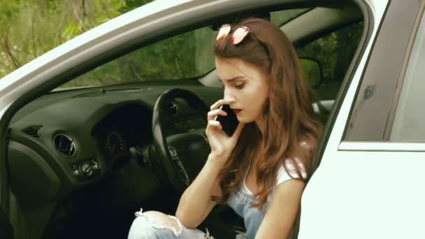 Jovem morena atraente fala em um telefone no carro — Vídeo de Stock