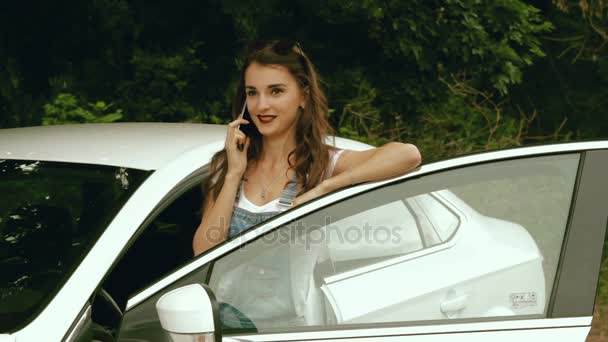 Hermosa chica con coche dice en un teléfono celular — Vídeo de stock