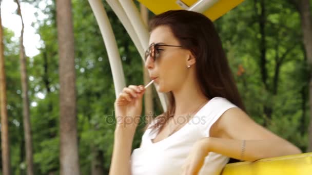 メガネ吸うロリポップでファッショナブルな若い女性 — ストック動画