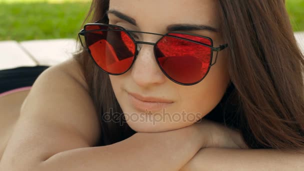 Atractiva joven en gafas de espejo yacen en la playa — Vídeo de stock