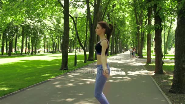 Karcsú lány a parkban, és ugrik a kötél — Stock videók