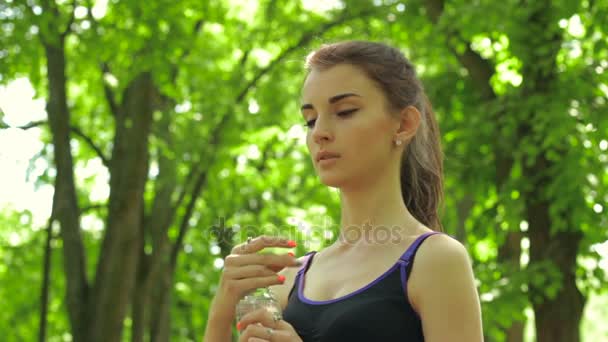 Carino ragazza atletica prendendo una bottiglia d'acqua — Video Stock