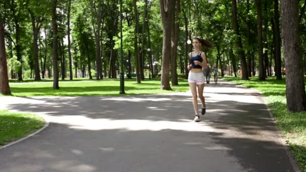 Skinny girl runs through the Park in summer short shorts — Stock Video