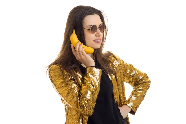 Fröhliche brünette Frau in goldener Jacke mit einer Banane — Stockfoto