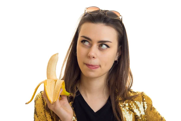 Morena mujer en chaqueta dorada comiendo un plátano —  Fotos de Stock