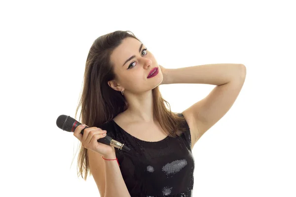 Mignonne femme en robe noire chantant un karaoké avec microphone — Photo