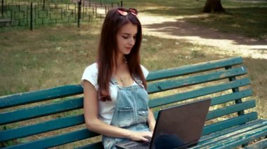 şirin esmer bir bankta oturan ve laptop arıyorum