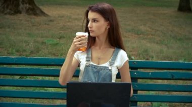 genç çekici esmer kahve içer ve bir dizüstü bilgisayar dik dik bakıyor