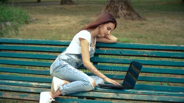 Hermosa joven morena sonriendo y impresiones en el ordenador portátil — Vídeos de Stock