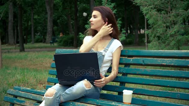 Очаровательная женщина сидит на улице и на отпечатках ноутбука — стоковое видео