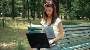 çekici genç kız gözlük oturur Park ile dizüstü açar