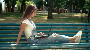 Genç Kız parkta bir bankta oturan ve laptop arıyorum