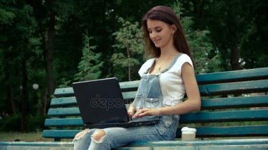 Yaz ve bir dizüstü bilgisayar üzerinde parmak sırasında parkta oturan Bayan