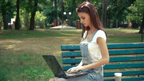 Wunderbare Brünette sitzt auf einer Bank mit einem Laptop — Stockvideo