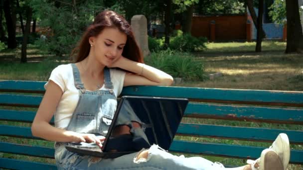 Lachende jongedame, liggend op de Bank met een laptop — Stockvideo