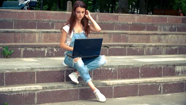 Women sitting on the steps in with a laptop — Stock Video