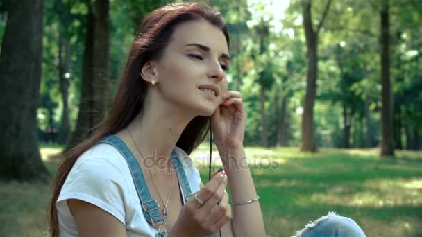 Krásná mladá brunetka vloží sluchátka v uších a poslouchá hudbu — Stock video