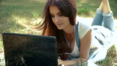 çim üzerinde yalan büyük siyah dizüstü bilgisayar ile güzel kız