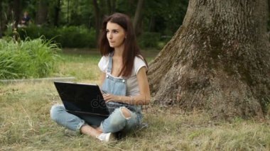 Yaz çimlerde oturan büyük dizüstü bilgisayar ile genç sevimli kız