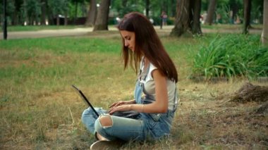 Pin-up kızları parmak bir ağacın yanında otururken dizüstü bilgisayarınızda giydi