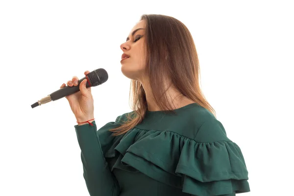 Чувственная молодая девушка в зеленом платье поет песню в микрофоне — стоковое фото