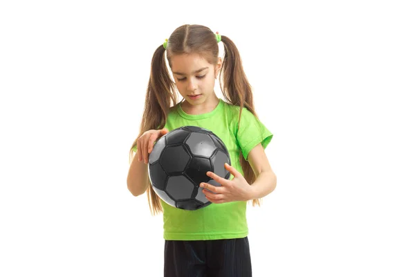 Little girl in green sports uniform with soccer ball in hands — Stock Photo, Image