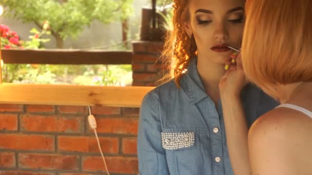 Maquillaje artista sosteniendo un pincel y pintura brillo labios joven chica — Vídeos de Stock