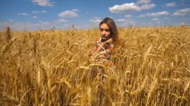 genç kız bir buğday alanında oturur ve kameraya doğru görünüyor