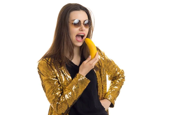 Веселая дама в золотой куртке поет банану — стоковое фото