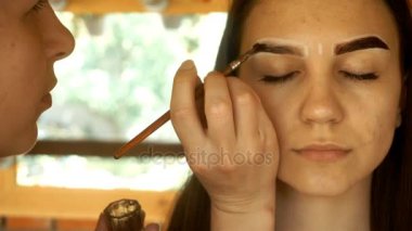 Bir fırça tutan profesyonel makyaj sanatçısı ve kaşları boya