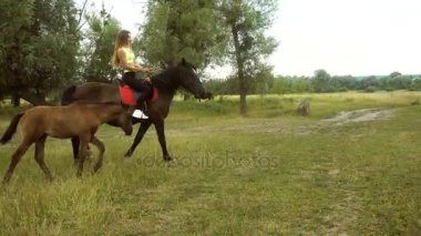 ince Bayan yavru yakınındaki çimenlerin üzerinde at sürmek