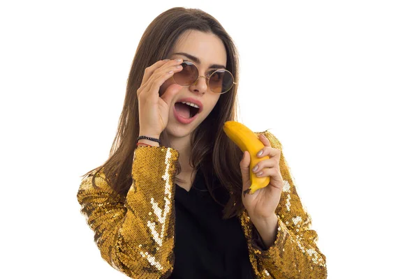 Веселая стильная женщина в золотой куртке с бананом в руках — стоковое фото