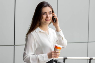 Beyaz bluz içinde çekici hanım gülümsüyor ve telefonda diyor