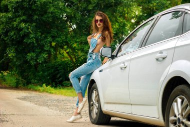 Kot pantolon seksi genç esmer beyaz bir araba arasında genel stans
