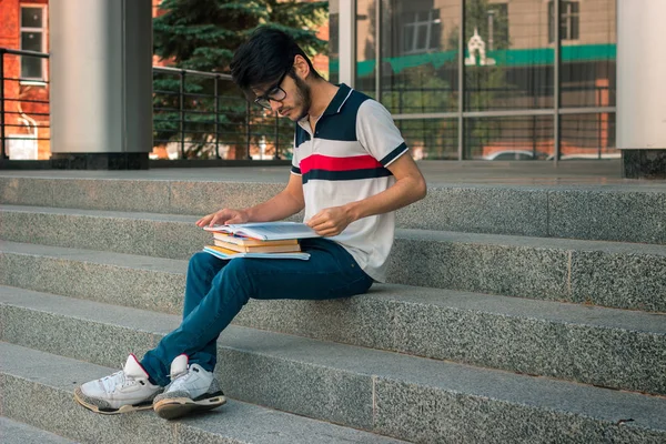 Jonge stijlvolle man leest boeken zittend op de trap — Stockfoto